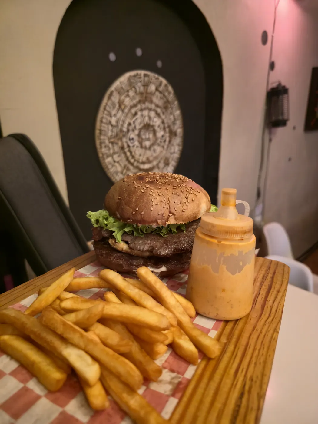 Hamburguesa con papas frente a decoración inspirada en el Templo